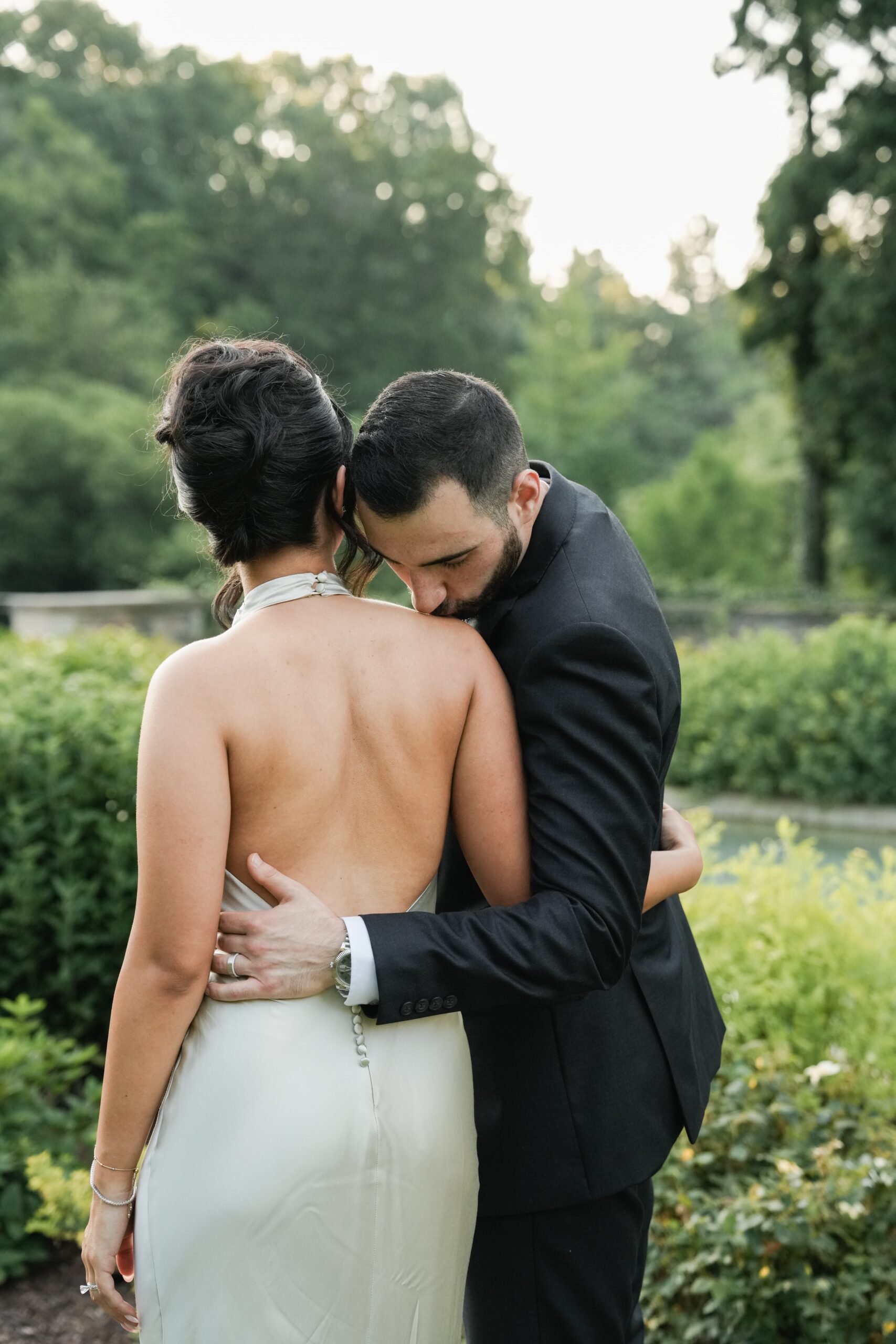 A couple embraces tenderly in a lush outdoor setting.