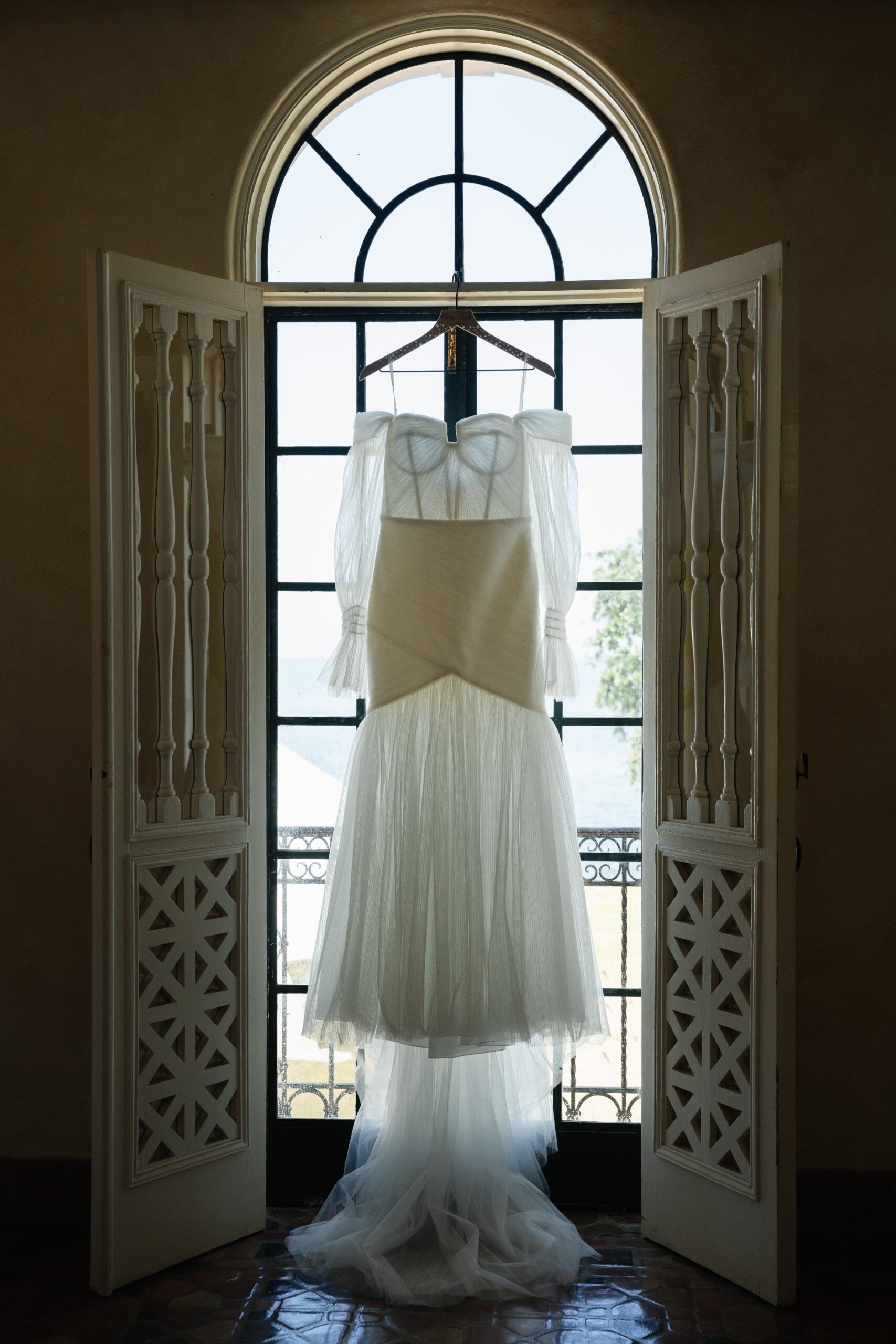 Elegant white dress hanging in front of a vintage window.