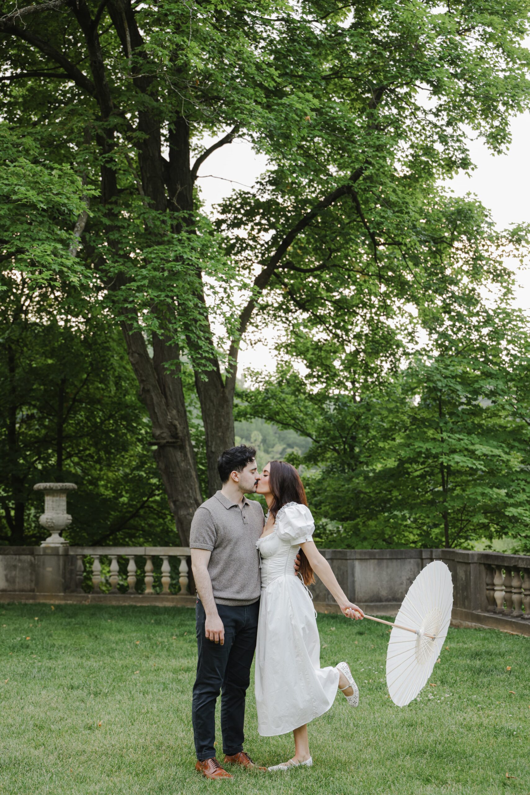 Couple sharing a tender moment outdoors surrounded by lush greenery.
