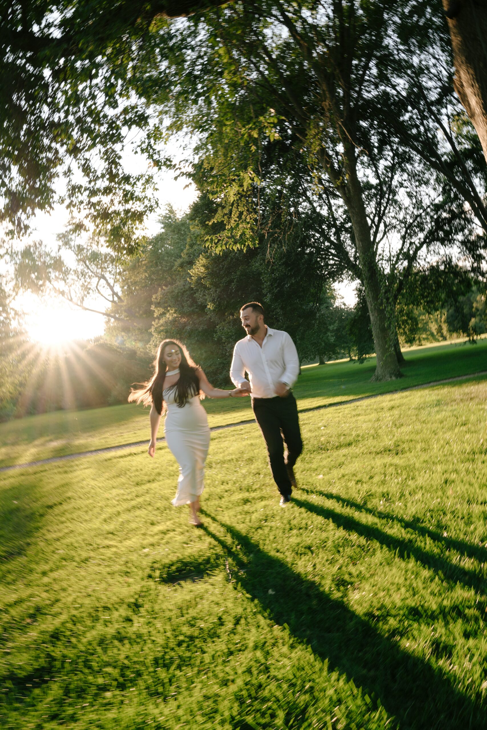Couple joyfully running hand-in-hand in a sunlit park.