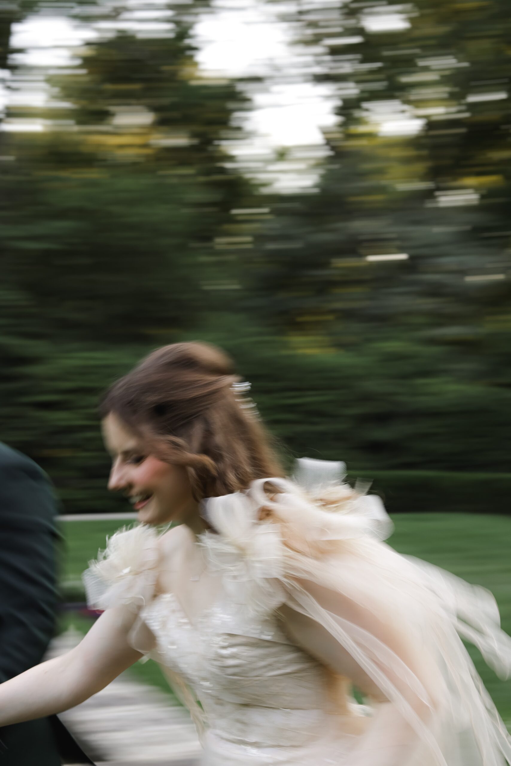 A blurred image of a woman in a white dress running outdoors.