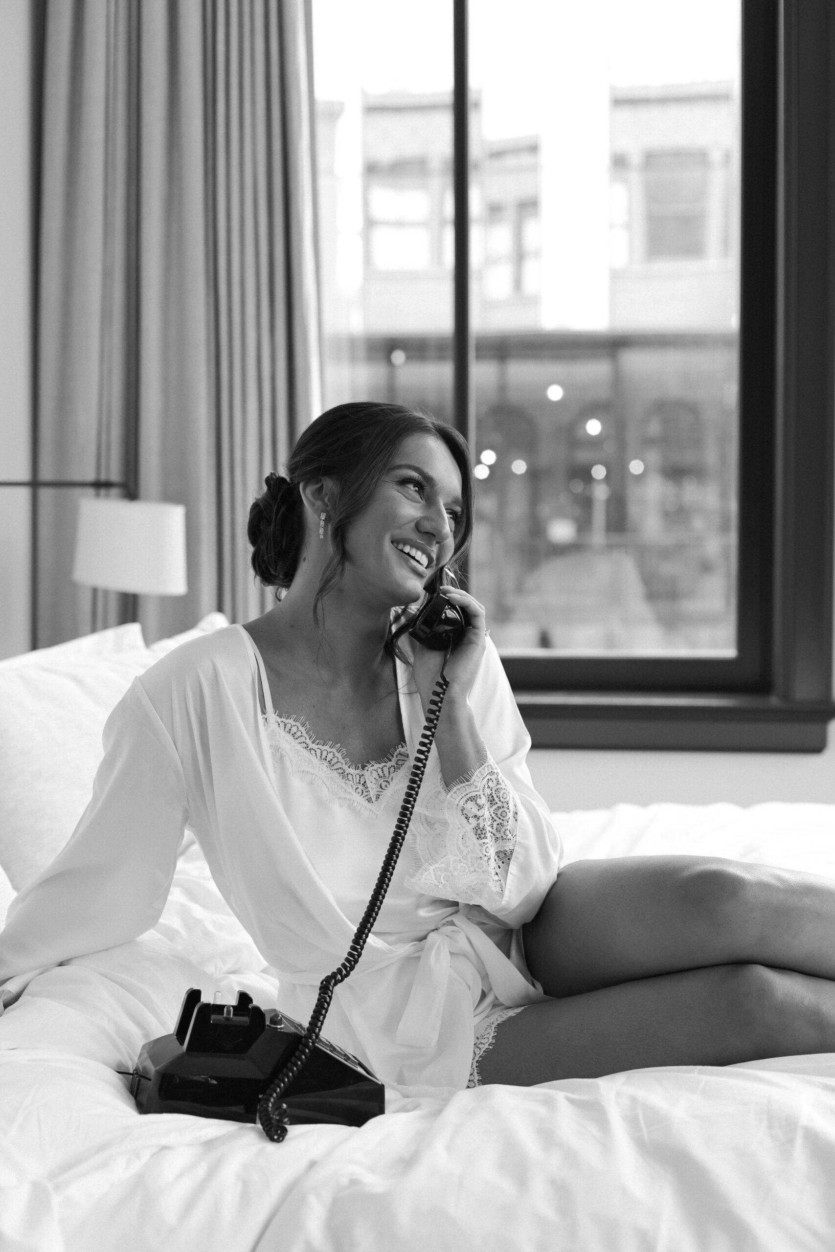 A woman smiling while talking on the phone in a cozy room.