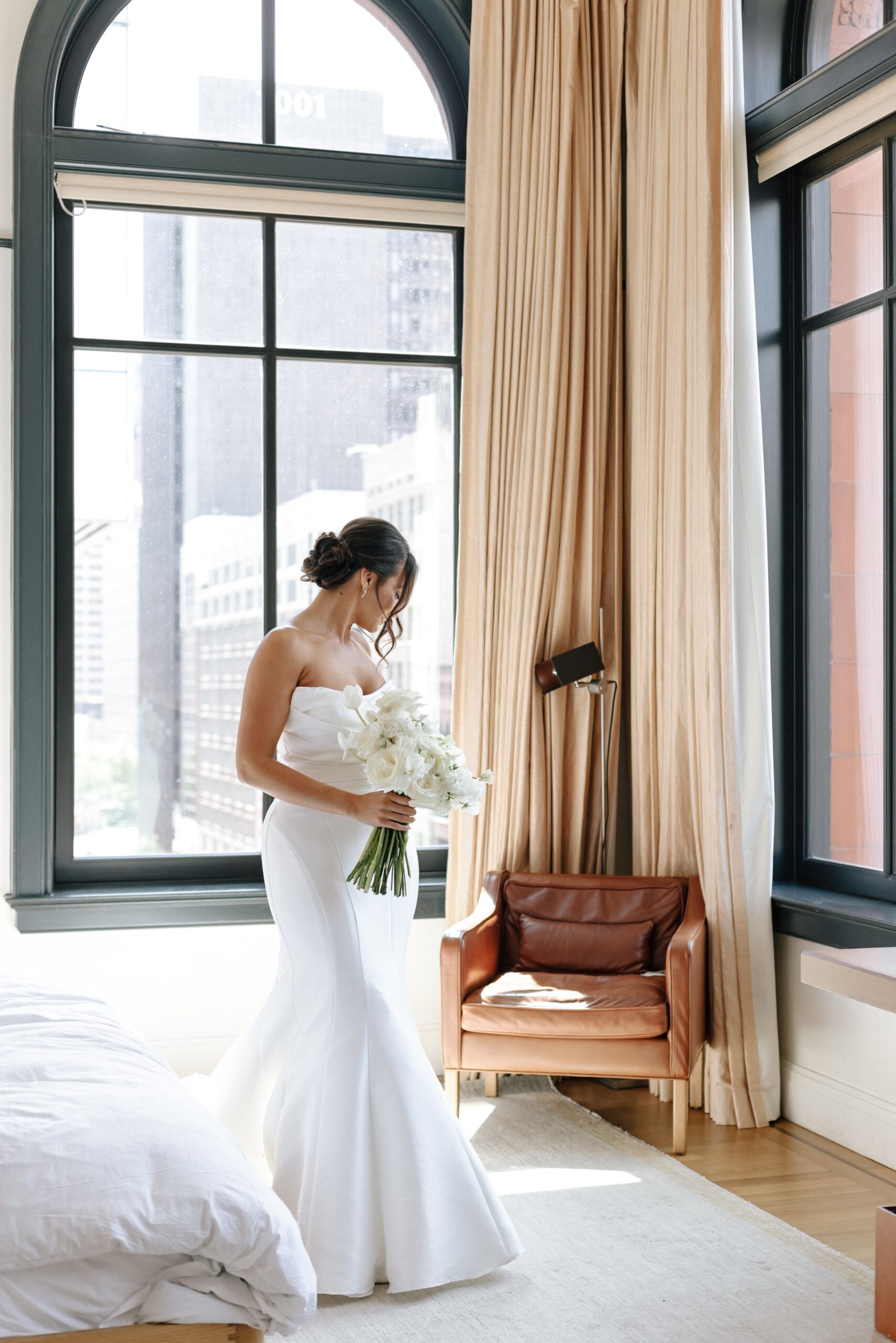 Bride in white gown holding flower bouquet.